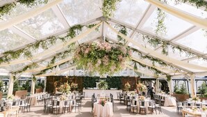 A tented outdoor event space with tables set for dining, surrounded by greenery and flowers. - Northern Liberties Epic Retreat-Huge Yard/Fire Pit (Philadelphia)