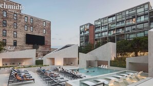 A rooftop pool area with lounge chairs and a swimming pool, surrounded by modern buildings with a sign that reads "Home of Schmidts Beer and Ale". - Northern Liberties Epic Retreat-Huge Yard/Fire Pit (Philadelphia)