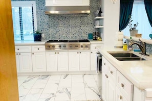 A kitchen with white cabinets, a stainless steel stove, and a tiled backsplash.