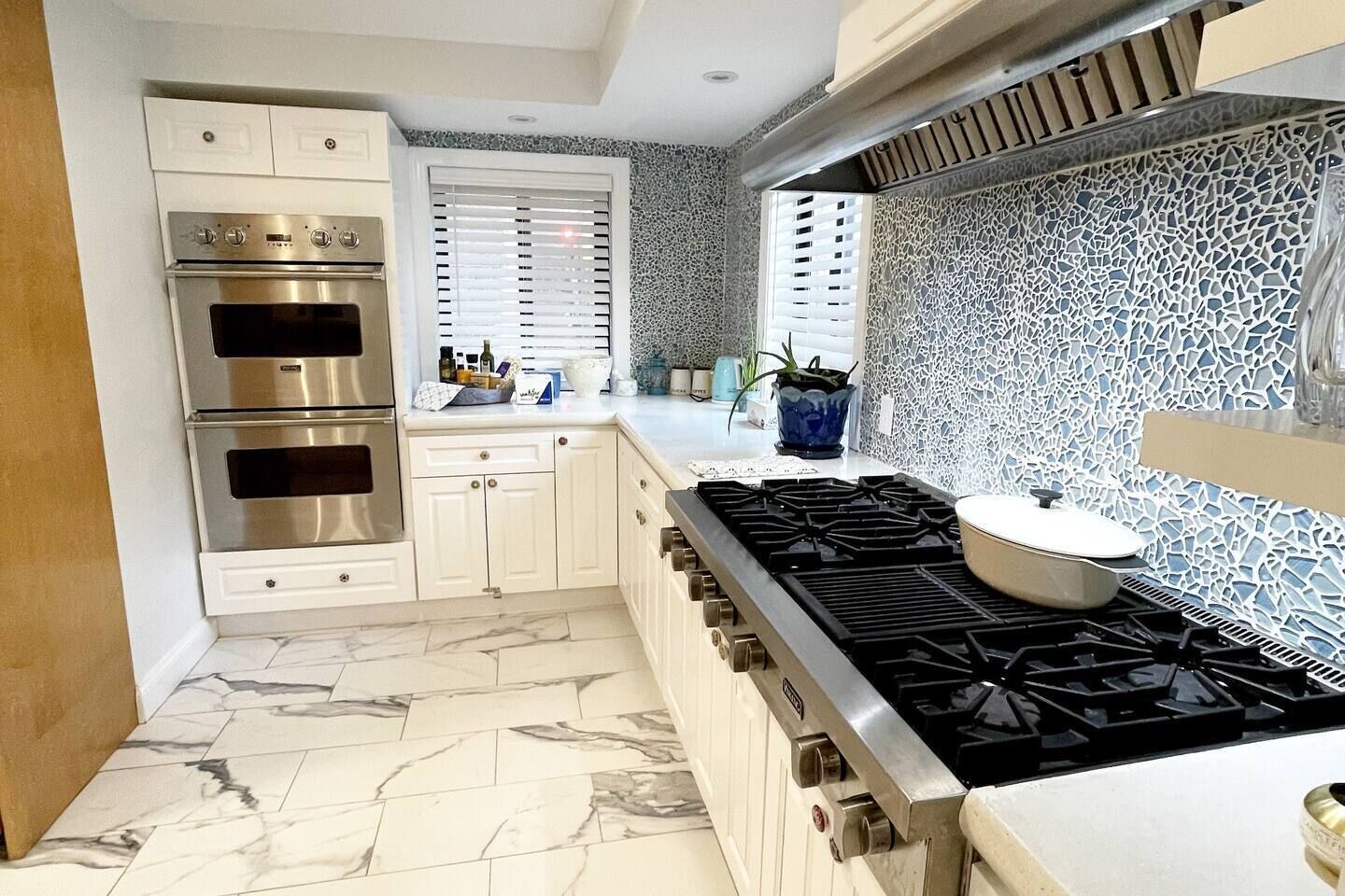 Una cucina moderna con elettrodomestici in acciaio inossidabile, mobili bianchi e un backsplash decorato.