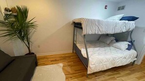 Une petite pièce, de taille modeste, comprenant un lit superposé, un canapé et une plante en pot.