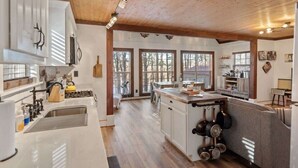 A spacious kitchen with wooden beams, large windows, and a central island with pots and pans. - Sunset Escape, Waterfront, Sleeps 6, Fishing, 2 Kayaks, Games, + Firepit! (Eatonton)