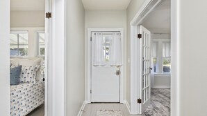 Un couloir avec une porte blanche, un lit à motifs et un tapis.