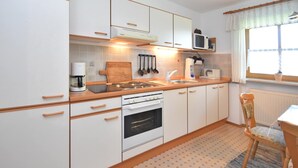 Une cuisine moderne avec des meubles blancs, un plan de travail en bois, une cuisinière et un four à micro-ondes.