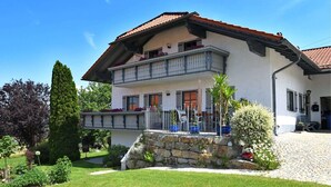 Une maison à deux étages avec un balcon, des marches en pierre et un jardin.