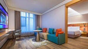 A modern hotel room with a sofa, a small table, a TV, and a bed. - Manxin Hotel Linfen Yingbin Avenue (Linfen)