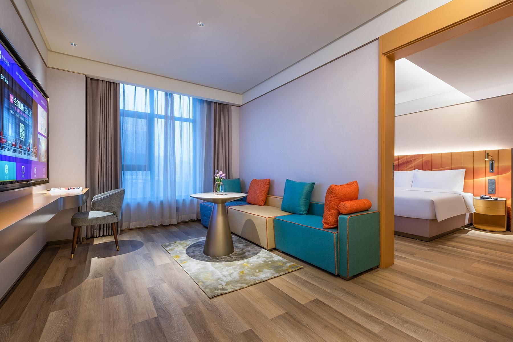 Una habitación de hotel moderna con sofá, una mesita, televisor y cama.