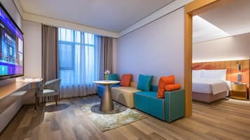 Una habitación de hotel moderna con sofá, una mesita, televisor y cama.