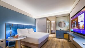 Habitación de hotel moderna con cama, mesita de noche y televisor mostrando un menú de servicio a la habitación.
