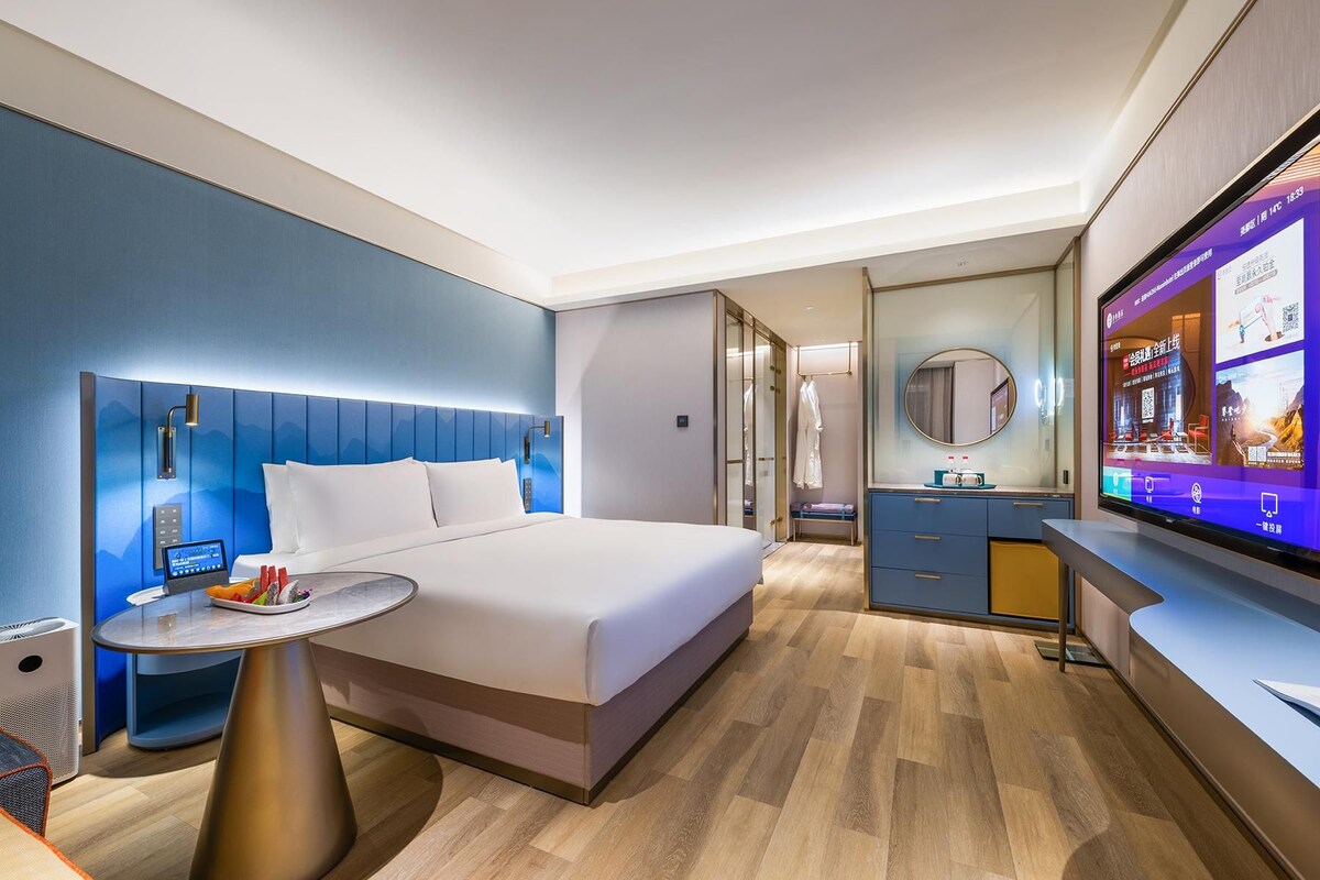 Habitación de hotel moderna con cama, mesita de noche y televisor mostrando un menú de servicio a la habitación.