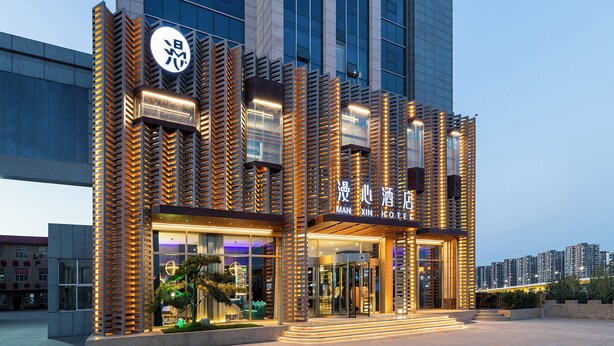 A modern hotel building with a prominent entrance, large windows, and a well-lit facade. - Manxin Hotel Linfen Yingbin Avenue (Linfen)