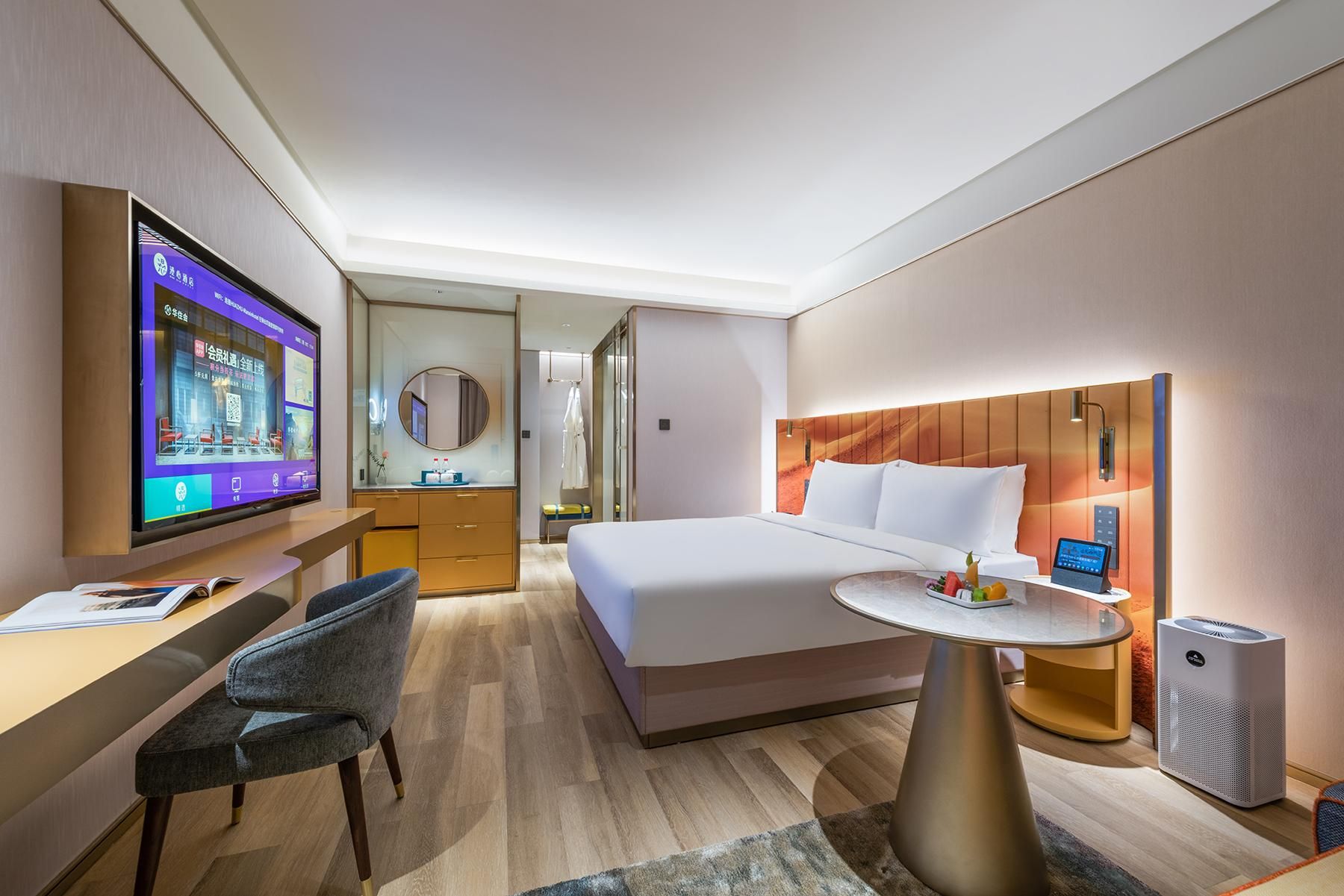 A hotel room with a bed, bedside table, TV, desk, chair, and a mirror.