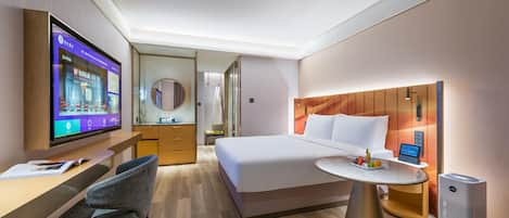 A hotel room with a bed, bedside table, TV, desk, chair, and a mirror.