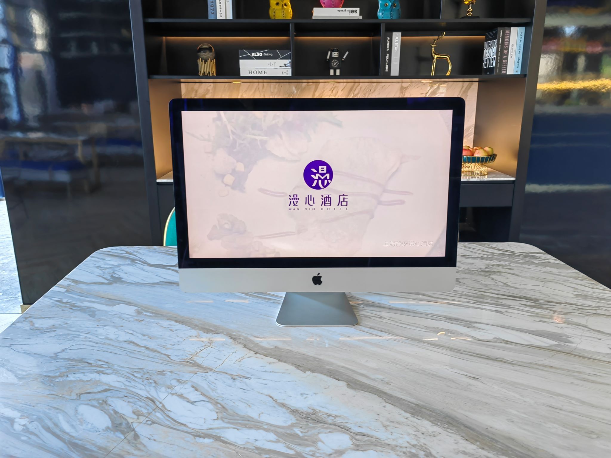 A computer monitor on a marble table displaying a hotel sign.