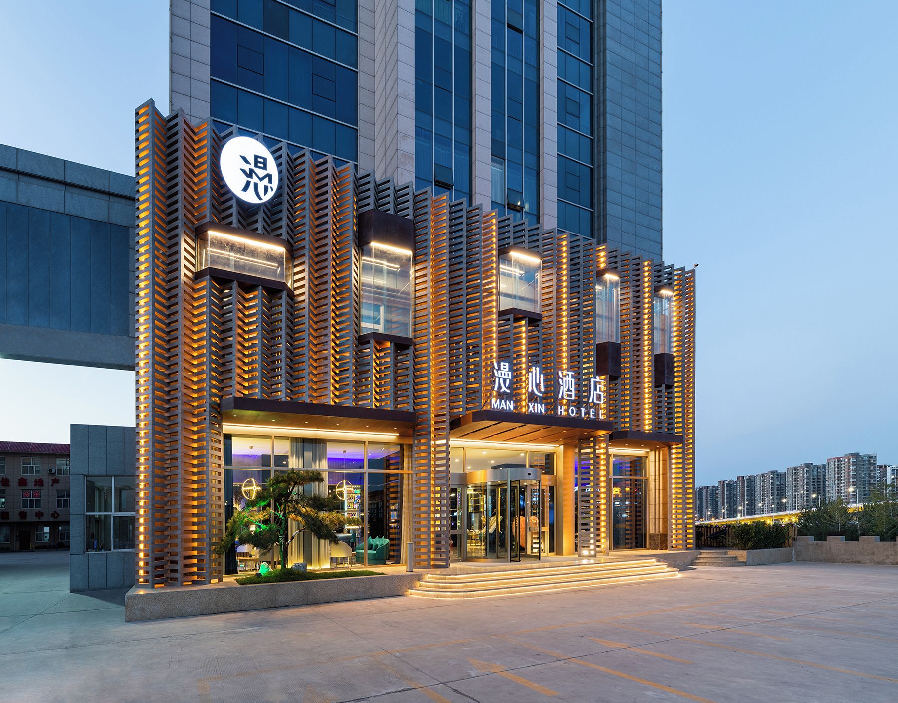 A modern hotel building with a prominent entrance, large windows, and a well-lit facade.