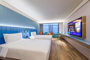 Habitación de hotel con dos camas, un televisor en la pared y zona de estar con vista a la ciudad.