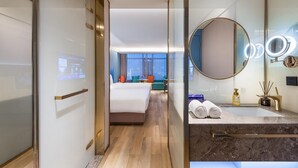 A hotel room with a bed, a seating area with a view, a bathroom with a mirror and toiletries. - Manxin Hotel Linfen Yingbin Avenue (Linfen)