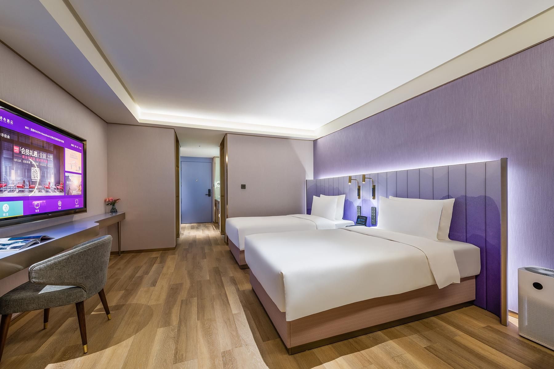 A hotel room with a bed, a desk, and a television.