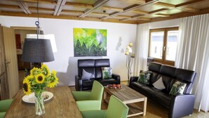 Un salon avec un plafond en bois, un tableau, un canapé, une table basse et une table à manger avec des chaises.