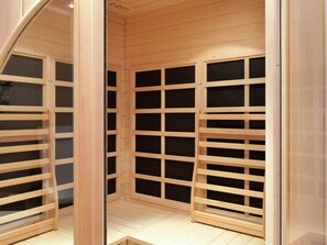 A wooden room with a slatted ceiling and floor, featuring a central column and a mirrored wall. - Wohnung in Ruhmannsfelden nahe Skipisten (Ruhmannsfelden)