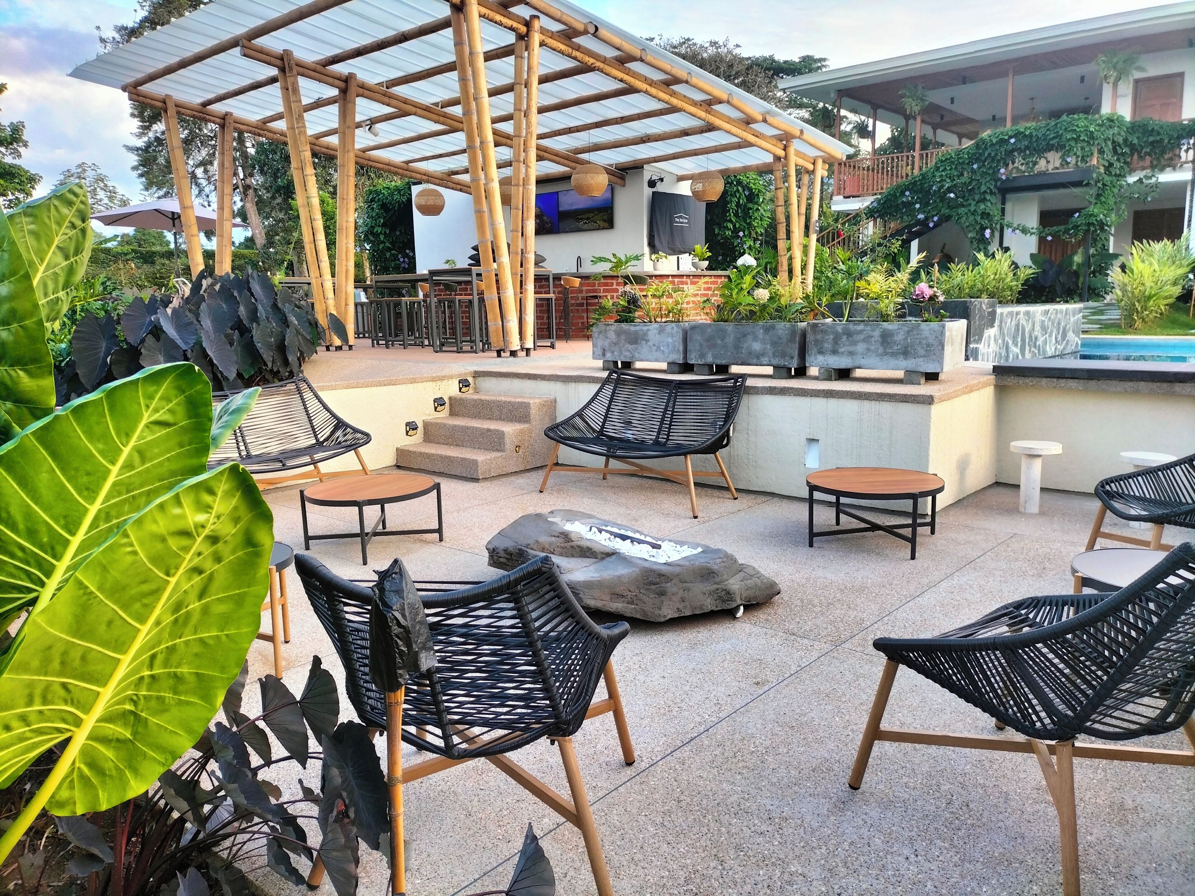 Un espace extérieur aménagé en terrasse, avec une pergola en bambou, des sièges et une piscine.