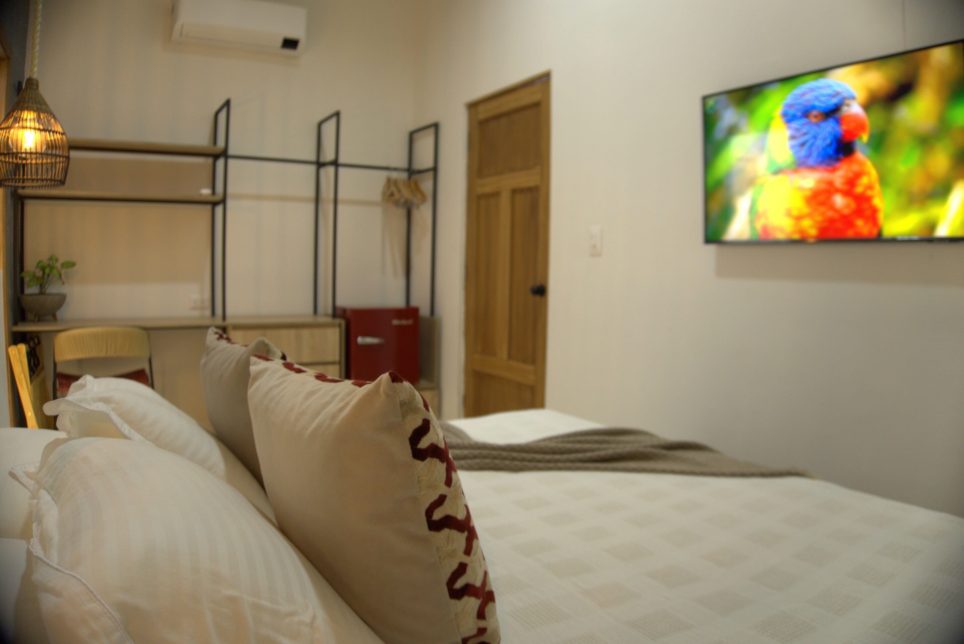 Une chambre à coucher avec un lit, des oreillers, une télévision, un bureau et une chaise.