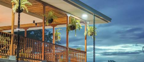 A modern house with a balcony, wooden railings, and hanging plants.