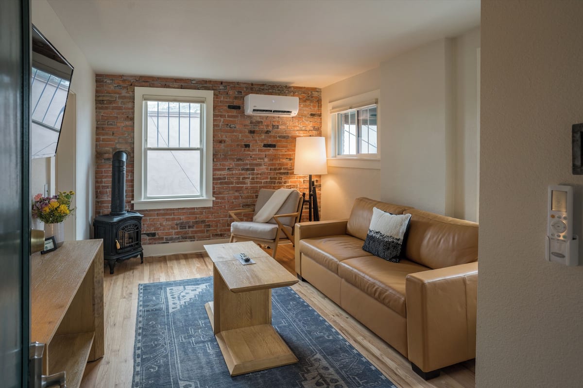 A cozy living room with a brick wall, a sofa, a coffee table, a lamp, and a fireplace.