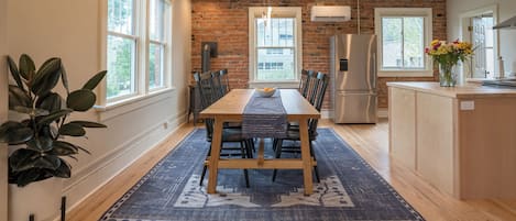 Une cuisine moderne avec un mur en briques, une table à manger en bois et des appareils électroménagers intégrés.