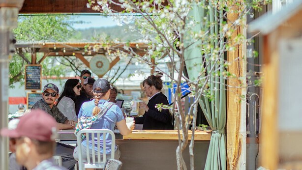 An outdoor seating area with tables and chairs, a counter, and a view of the outdoors. - Leland House Suites of Durango (Durango)
