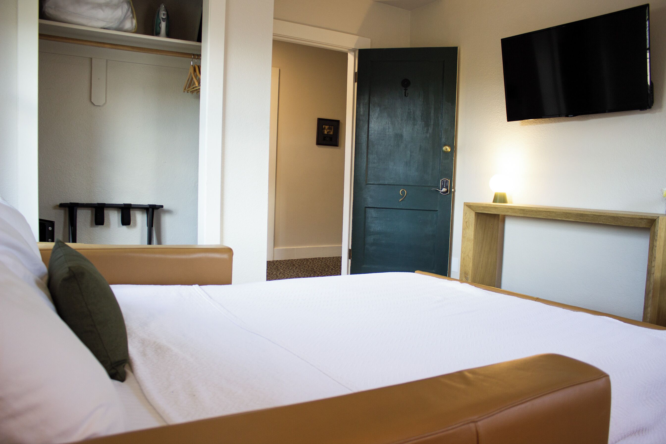 Une chambre d’hôtel équipée d’un lit, d’une table de chevet, d’une armoire et d’un téléviseur fixé au mur.