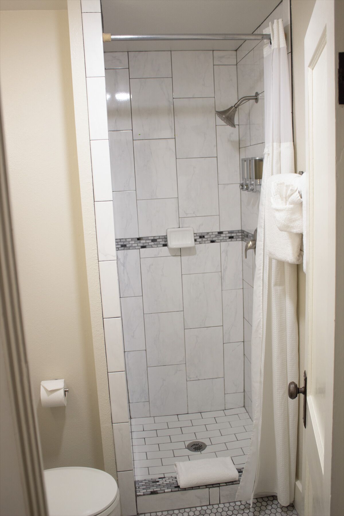 Un baño con ducha, inodoro y un perchero para toallas.