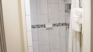 Un baño con ducha, inodoro y un perchero para toallas.