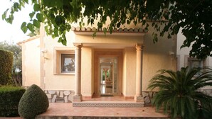 A building with a stone entrance, columns, and a tiled porch. - Villa Steps from the Sea (Denia)