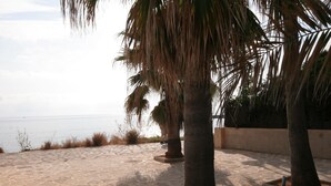 A paved walkway with palm trees and a view of the sea. - Villa Steps from the Sea (Denia)