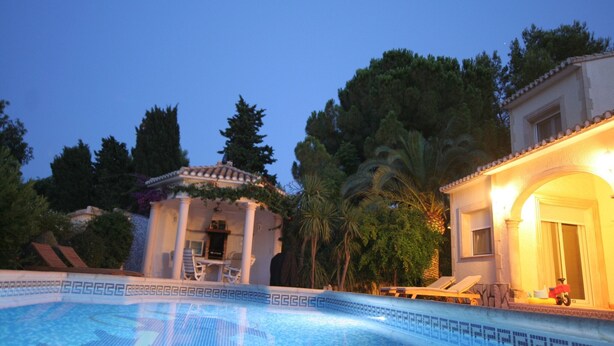 A swimming pool with a geometric tile pattern, surrounded by lounge chairs and a pergola. - Villa Steps from the Sea (Denia)