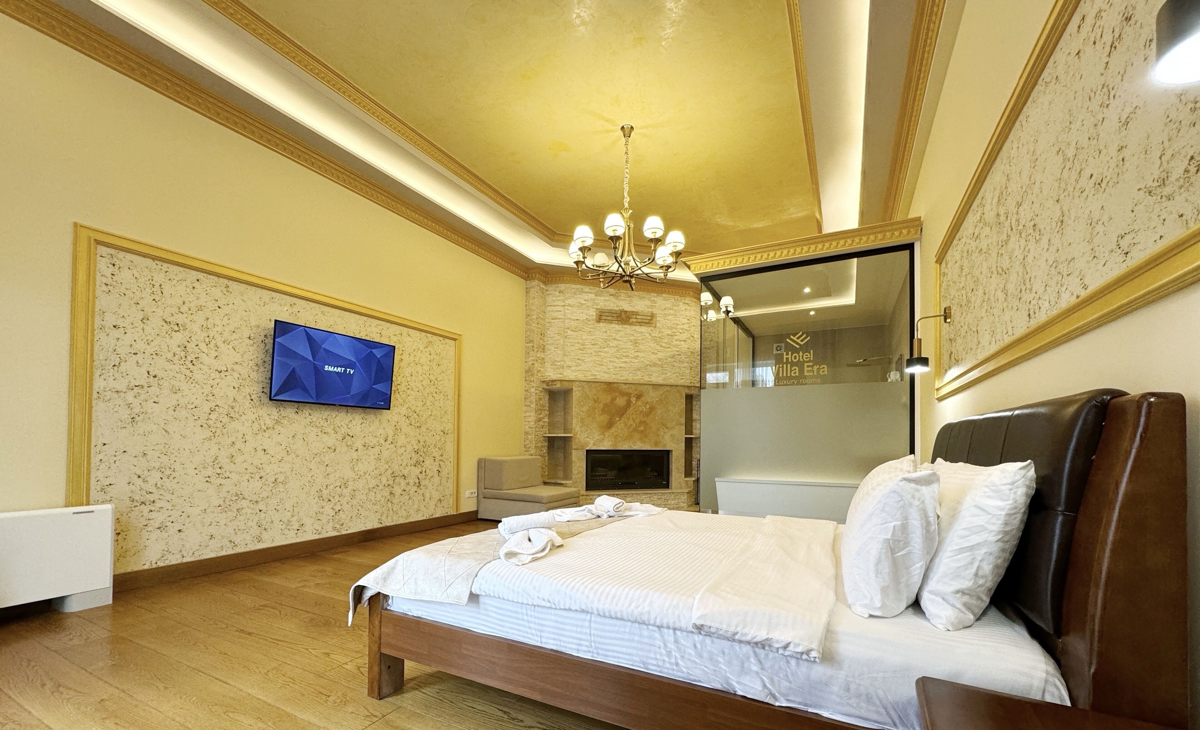 Una camera d'albergo con un letto, una televisione, un camino e un lampadario.