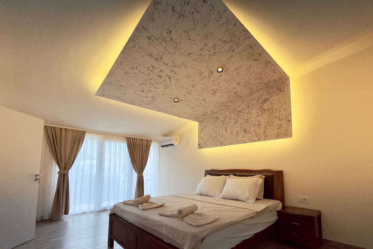 Ein Hotelzimmer mit Bett, Nachttisch und einer Decke mit einzigartigem Design.
