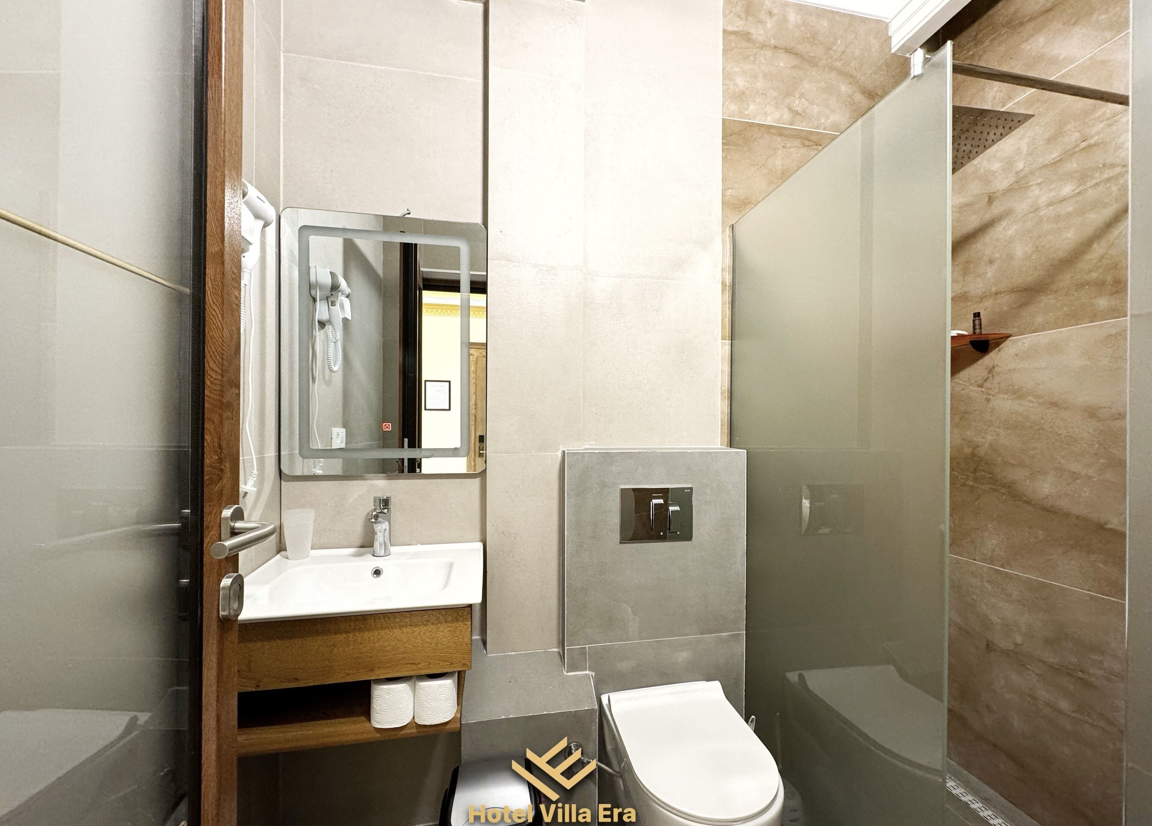 A modern bathroom with a glass shower enclosure, a sink with a mirror, and a toilet.