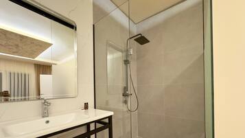 Une salle de bain moderne avec un grand miroir, un lavabo et une douche à parois de verre.