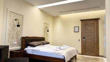 Een hotelkamer met een bed, nachtkastjes, een stoel, een deur en een wandlamp.