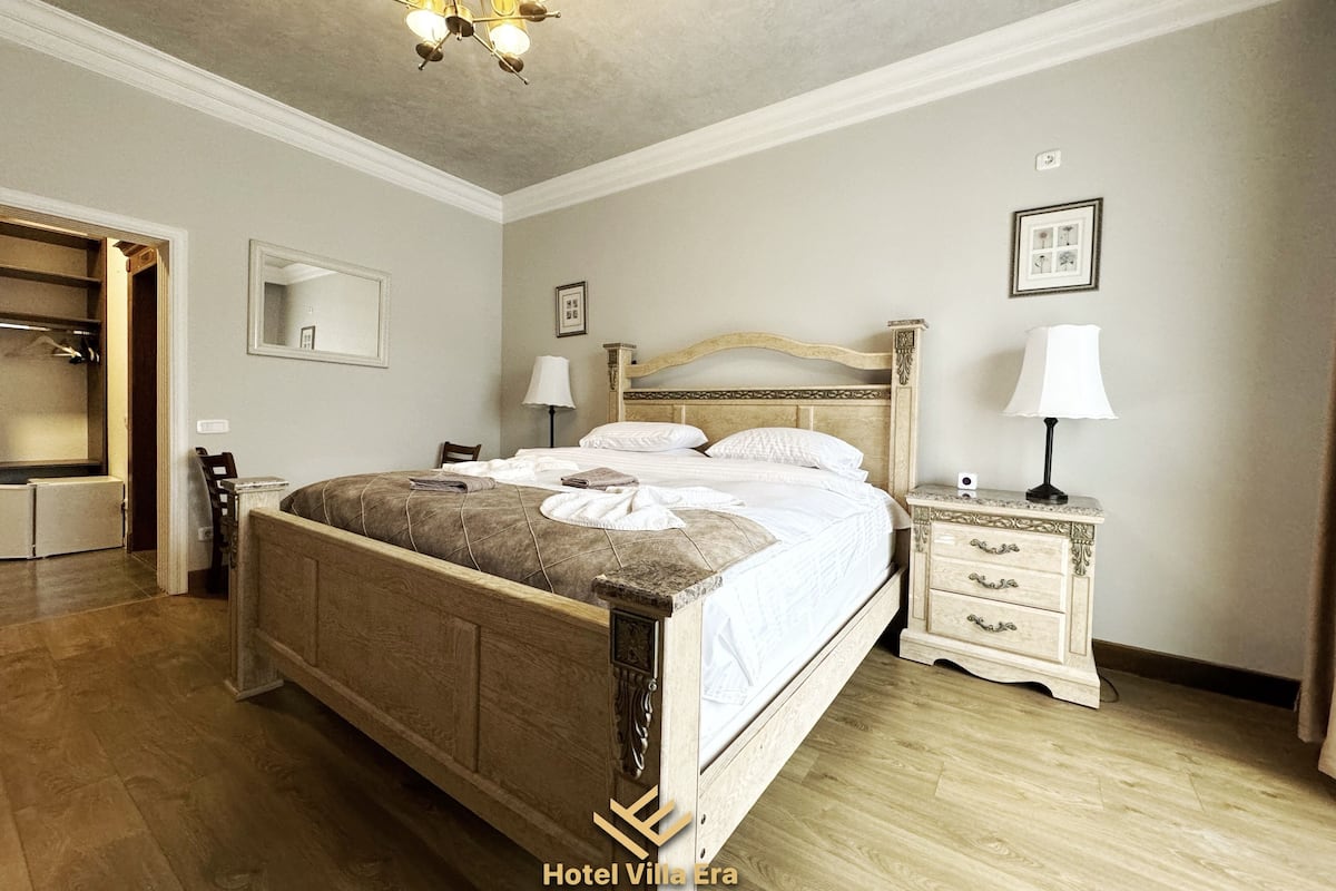 Ein Schlafzimmer mit einem Holzbett, Nachttischen, einem Spiegel und einer Pendelleuchte.
