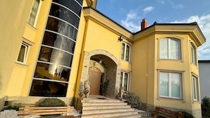 Un edificio amarillo con una gran entrada arqueada, escalones que llevan a la puerta y una estatua de león al frente.