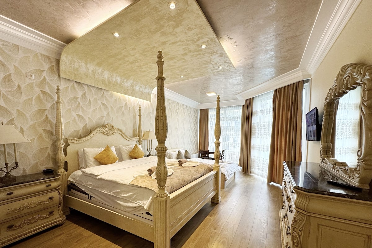 Ein luxuriöses Schlafzimmer mit Himmelbett, aufwendiger Wandgestaltung und einem großen Spiegel.