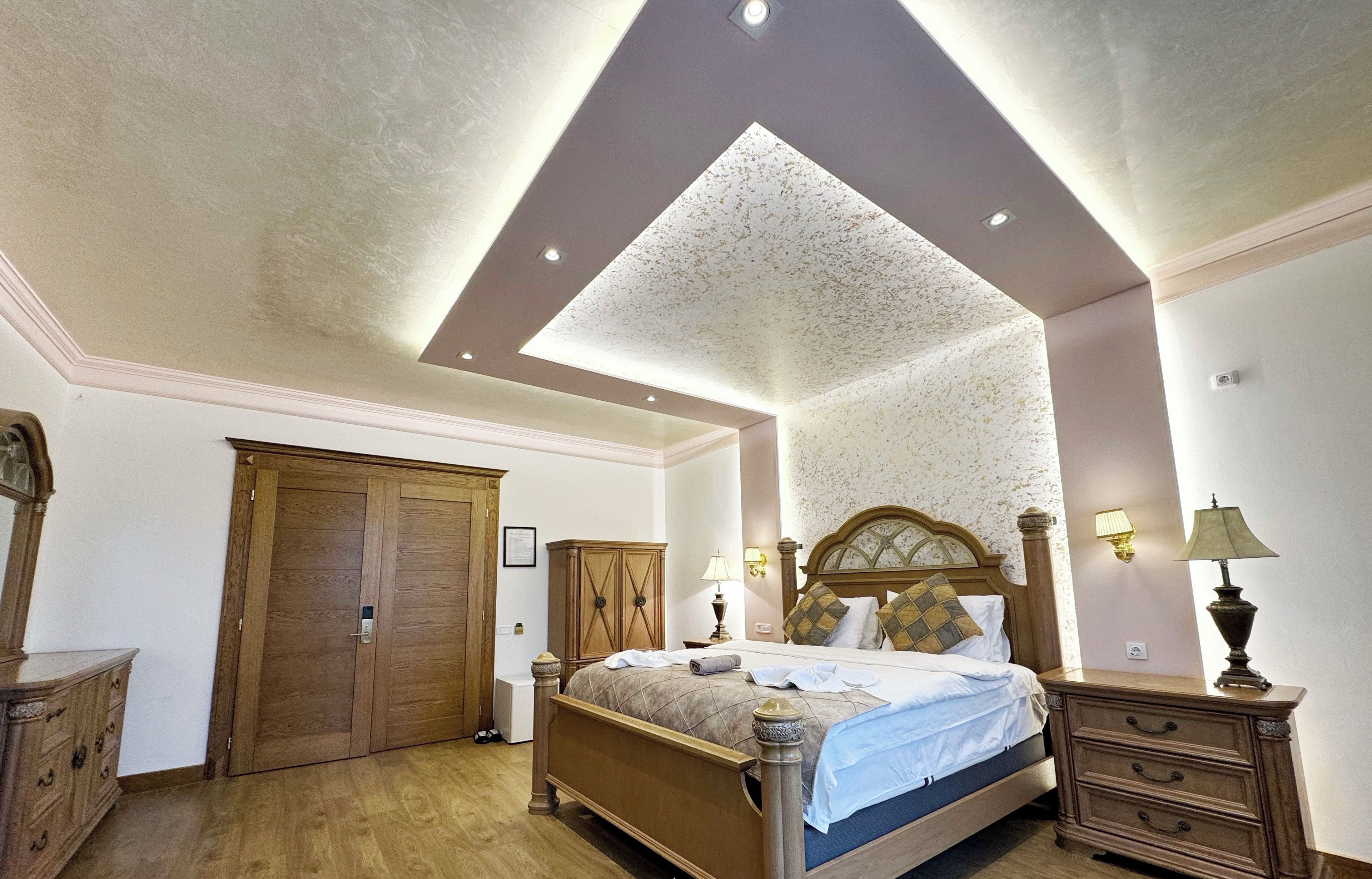 Un dormitorio con cama de madera, armario, cómoda y lámpara en el techo.