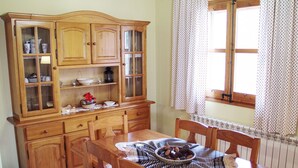Une salle à manger traditionnelle, avec des meubles en bois, un grand buffet aux portes vitrées et une fenêtre agrémentée de rideaux.