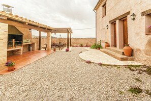 A patio area with a pergola, outdoor seating, and a gravel path leading to a building with a wooden door. - Mansion in Maians with Private Pool (Maians-Castellfollit del Boix)