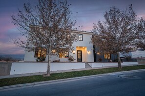 A modern two-story house with a white exterior, a front door, and a small porch area. - Spacious Brand New Home! Lots of courtyard space and fun for all. (Hurricane)
