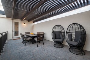 An outdoor patio with a table and chairs, a covered area with a ceiling, and two wicker chairs. - Spacious Brand New Home! Lots of courtyard space and fun for all. (Hurricane)