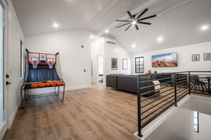 A spacious living area with a basketball hoop, a grey sofa set, a dining table, and a staircase. - Spacious Brand New Home! Lots of courtyard space and fun for all. (Hurricane)